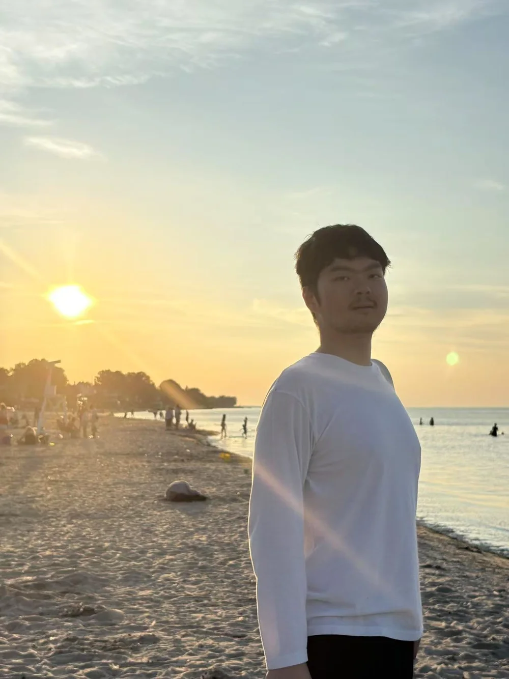 Jiayu Qin standing by the shoreline at sunset